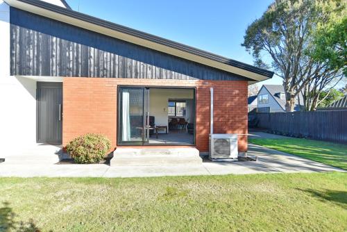 a brick house with a glass door on a yard at Lavandula 3 - Christchurch Holiday Homes in Christchurch