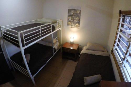 Cette petite chambre comprend 2 lits superposés et une lampe. dans l'établissement Kimberley Travellers Lodge - Broome YHA, à Broome
