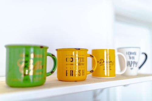 four yellow and green coffee mugs sitting on a shelf at ALBERT RESIDENCE Aparthotel in Braşov