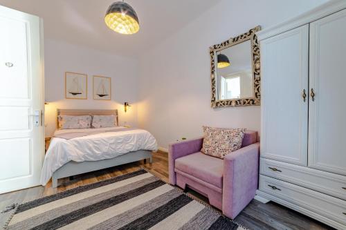 a bedroom with a bed and a chair and a mirror at ALBERT RESIDENCE Aparthotel in Braşov