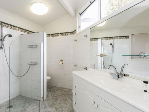 a white bathroom with a shower and a sink at Sunset Strip 4 in Torquay