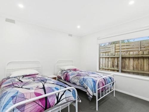 two beds in a white room with a window at Puebla Casa 17 in Torquay