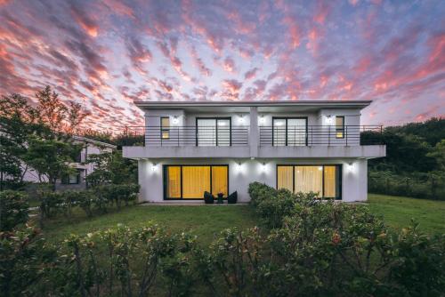 a white house with a sunset in the background at Kylin Villa resort Jeju in Seogwipo