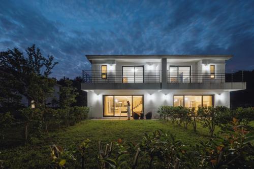 a large white house with a balcony at night at Kylin Villa resort Jeju in Seogwipo