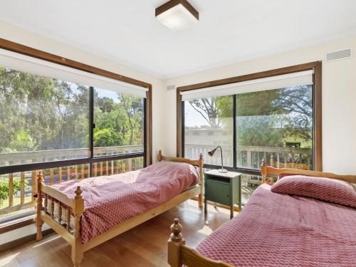 two beds in a bedroom with large windows at Inveray Beach House 11 in Torquay