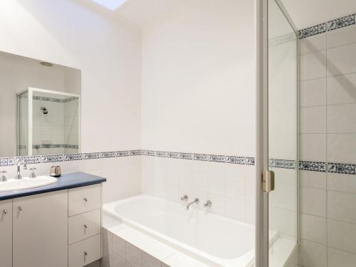 a white bathroom with a tub and a sink at Esplanade Frontage 219a in Torquay