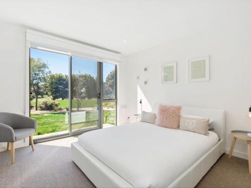a white bedroom with a bed and a large window at Coast Drive Beach and Golf 31 in Torquay