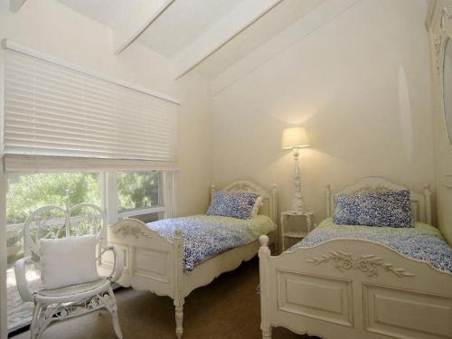 a white bedroom with two beds and a window at Barnett Place 6 in Torquay