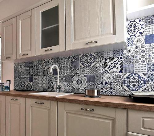 - une cuisine avec des placards blancs et du carrelage bleu et blanc dans l'établissement Paolanna Rooms Affittacamere, à Syracuse