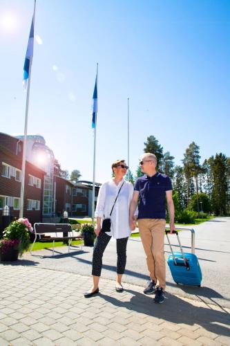 two older people walking down a street with a blue suitcase at Spa Hotel Härmä - Härmän Kylpylä in Ylihärmä