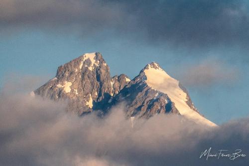 a mountain covered in snow and clouds in the sky at Le Bacchu Ber in Briançon
