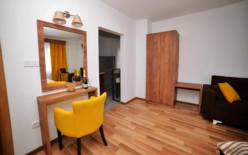 a living room with a yellow chair and a mirror at Studio apartmani Emili Bijeljina apartman br 1 in Bijeljina