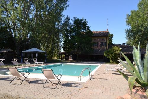 a swimming pool with chairs and a house in the background at La Locanda nel Frutteto in Rovereto