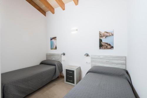 2 Betten in einem Zimmer mit weißen Wänden in der Unterkunft Villa Calan Bosch Es Bruc in Cala'n Bosch