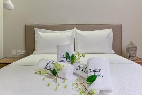 a white bed with towels and flowers on it at BLACKHAUS Apartments in Thessaloniki
