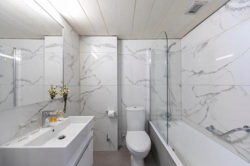 a white bathroom with a toilet and a tub and a sink at Odysseia Hotel Kapetanios in Limassol