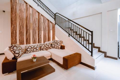 a living room with a couch and a stair case at Balitone Guest House in Denpasar