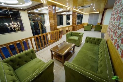a waiting room with green chairs and a table at Abhilashi Residency & Spa - Centrally Heated & Air Cooled in Manāli