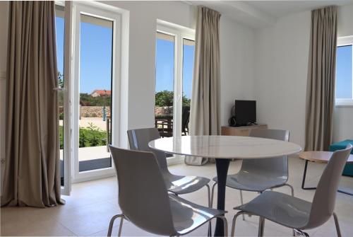 ein Esszimmer mit einem Tisch, Stühlen und Fenstern in der Unterkunft VILLA CALA, Hotel Rooms&Apartments in Novalja