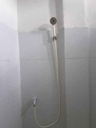 a shower with a hose attached to a wall at Penginapan Syariah in Parit