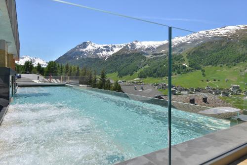 a pool of water with a mountain in the background at Alpen Resort Bivio in Livigno
