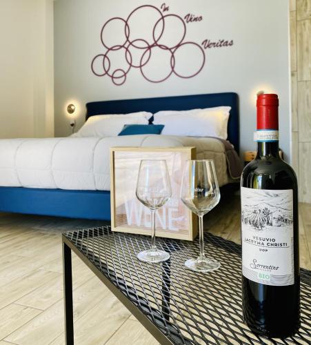 a bottle of wine and two glasses on a table at Vesuvio Inn Bed & Wine Experience in Boscotrecase