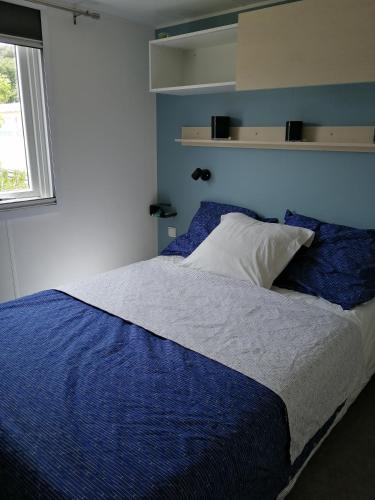 une chambre avec un lit avec des draps bleus et une fenêtre dans l'établissement MOBILE HOME 3 CHAMBRES, à Hyères