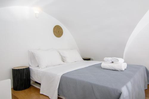 una camera da letto bianca con un letto e asciugamani di ArcadOIA House a Oia