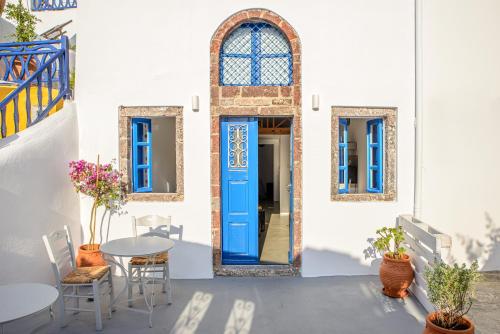 een blauwe deur op een wit gebouw met een tafel en stoelen bij ArcadOIA House in Oia