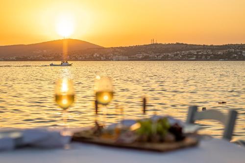 a table with wine glasses in front of the water at Villa Pietra in Ayvalık