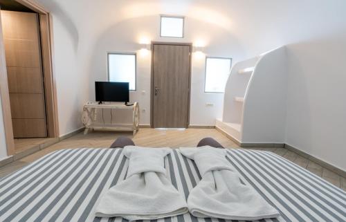 a living room with a bed and a television at Cally Cave House in Fira