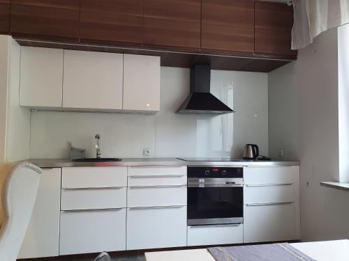 a kitchen with white cabinets and a black oven at Apartament Gdynia Świętojańska in Gdynia