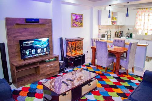 a living room with a television and a table with chairs at Lux Suites Nanyuki Business Apartment in Nanyuki