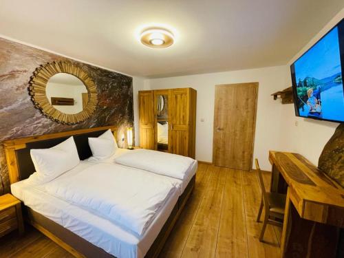 a bedroom with a white bed and a flat screen tv at Hotel Restaurant Unikat in Zeltingen-Rachtig