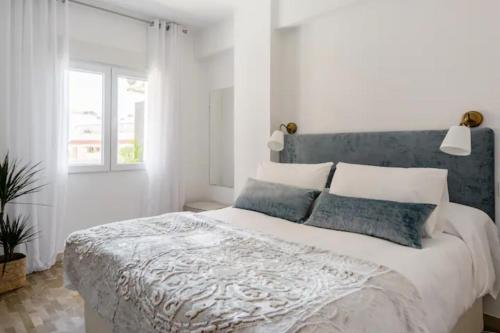a white bedroom with a large bed with a blue headboard at Apartamento Piccadilly Suite in Torremolinos