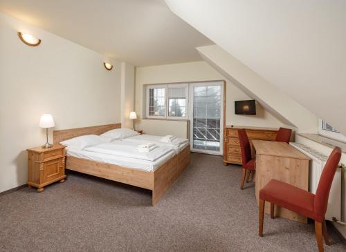 a bedroom with a bed and a desk and a window at Pension Trautenberk in Studenec