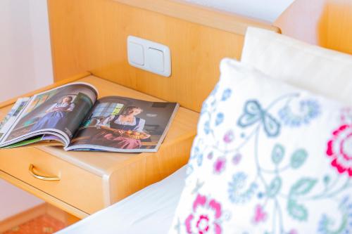 a magazine on a night stand next to a bed at Hotel garni Weberhäusl in Strobl