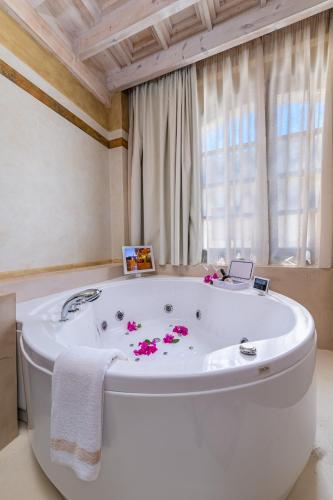 a white bath tub in a room with a window at 10GR Boutique Hotel & Wine Bar in Rhodes Town