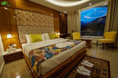- une chambre avec un grand lit et une grande fenêtre dans l'établissement Abhilashi Residency & Spa - Centrally Heated & Air Cooled, à Manali