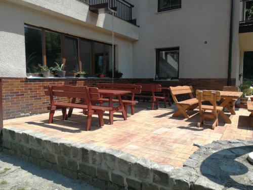 a patio with wooden tables and chairs in front of a building at Penzion U Klujů in Věstín