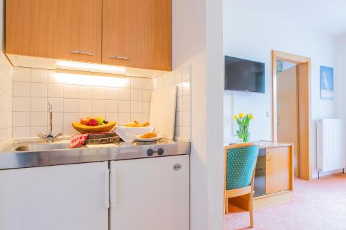 a kitchen with a sink and a bowl of fruit on the counter at Hotel garni Weberhäusl in Strobl