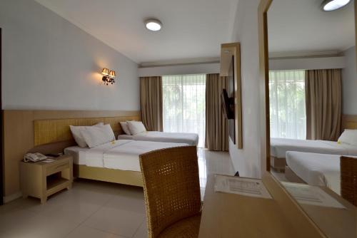 Habitación de hotel con 2 camas y sofá en Serela Kuta by KAGUM Hotels, en Kuta