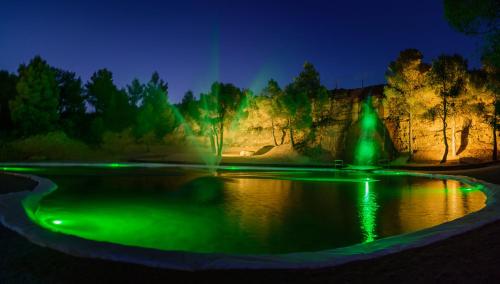 a pond lit up with green lights at night at Hotel La Parada del Compte in Torre del Compte