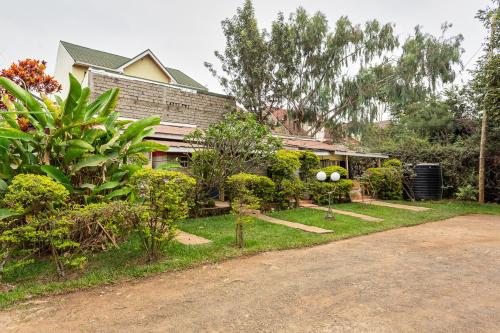 una casa con árboles y arbustos delante de ella en East of Eden, en Nairobi
