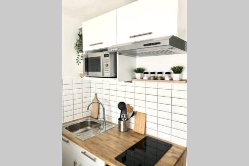 une cuisine avec un évier et un micro-ondes dans l'établissement Charmant studio à 400m de la plage avec piscine, à Guidel