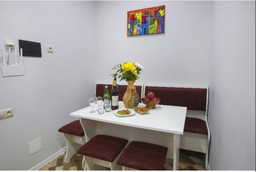 a white table with flowers and wine bottles on it at Leyla Apartments 1 in Baku