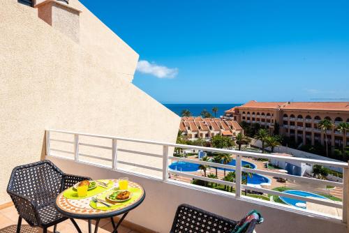 a balcony with a table and chairs and a pool at Tenerife South Apartments in Playa de las Americas