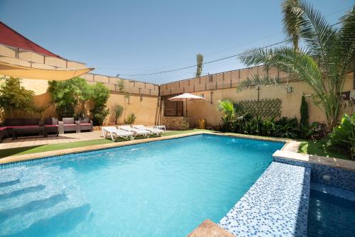 einen Pool in einem Garten mit Stühlen und einem Sonnenschirm in der Unterkunft Orient Villa-Dead Sea in Sowayma