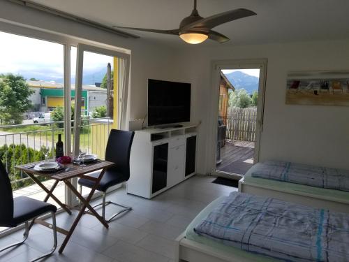 a living room with a television and a balcony at Terrace Apartment in Klaus