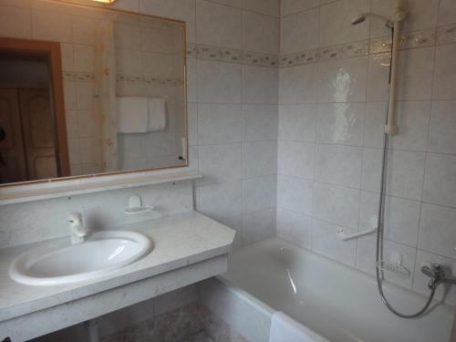 ein Badezimmer mit einem Waschbecken, einer Badewanne und einem Spiegel in der Unterkunft Kaiserhotel Neuwirt in Oberndorf in Tirol